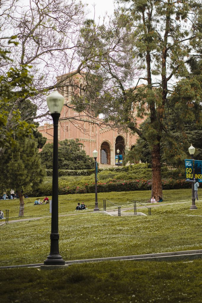 Scenic view of UCLA's lush campus with iconic buildings surrounded by trees and students enjoying the day.