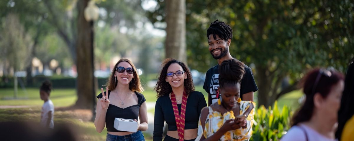 Smiling friends posing in a park on a sunny day, capturing joyful moments together.